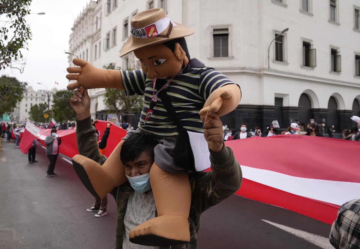 A man in the street carries a puppet on his shoulders.