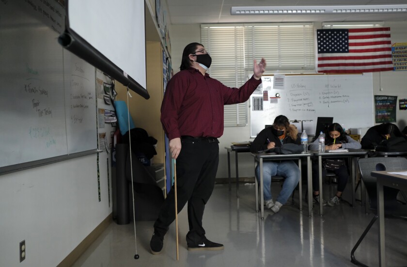 Anibal Hernandez teaches a history class while students write