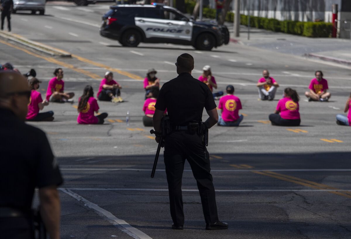 LAPD officers look at protesters sitting on the street