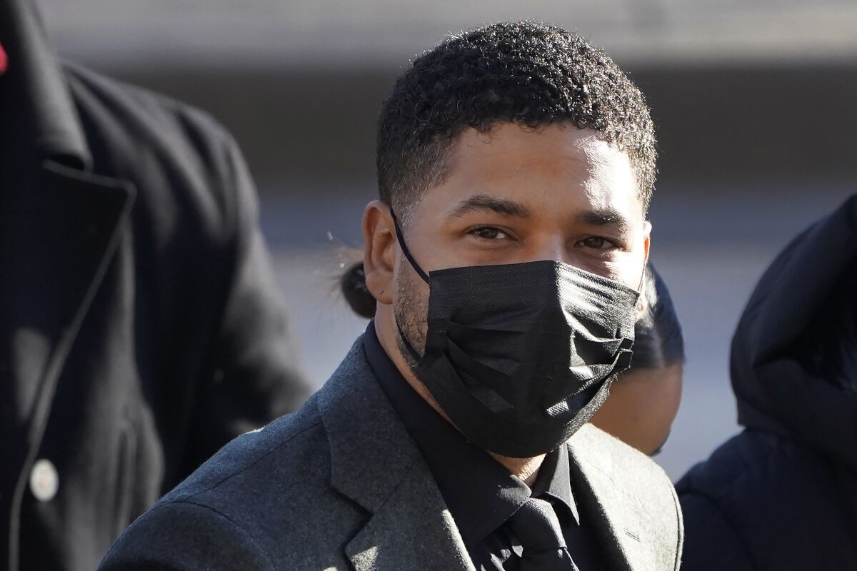 A man wearing a suit and a black COVID-19 facial mask arrives at a courthouse.