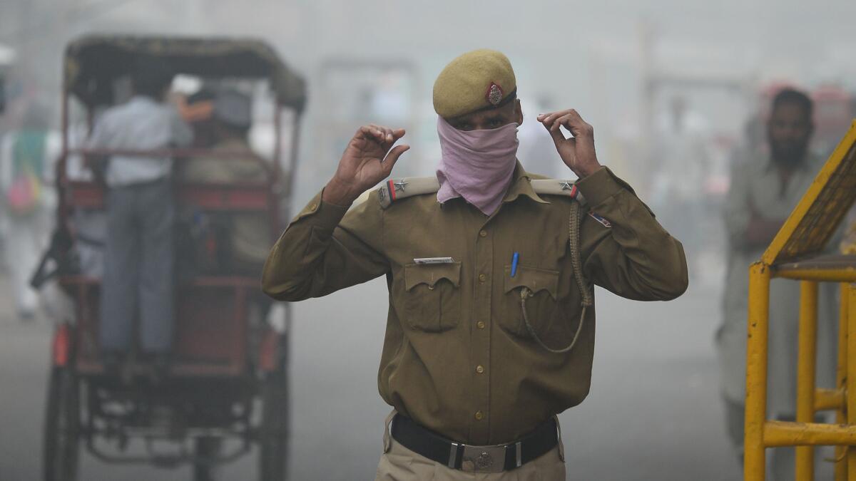 An Indian policeman tries to fend off the polluted air with a handkerchief.