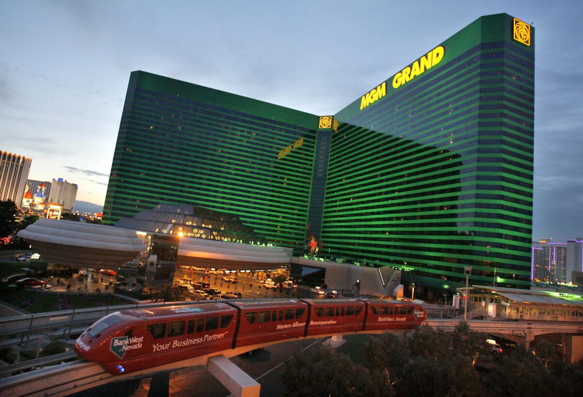 A monorail train passes a big, green-striped building.