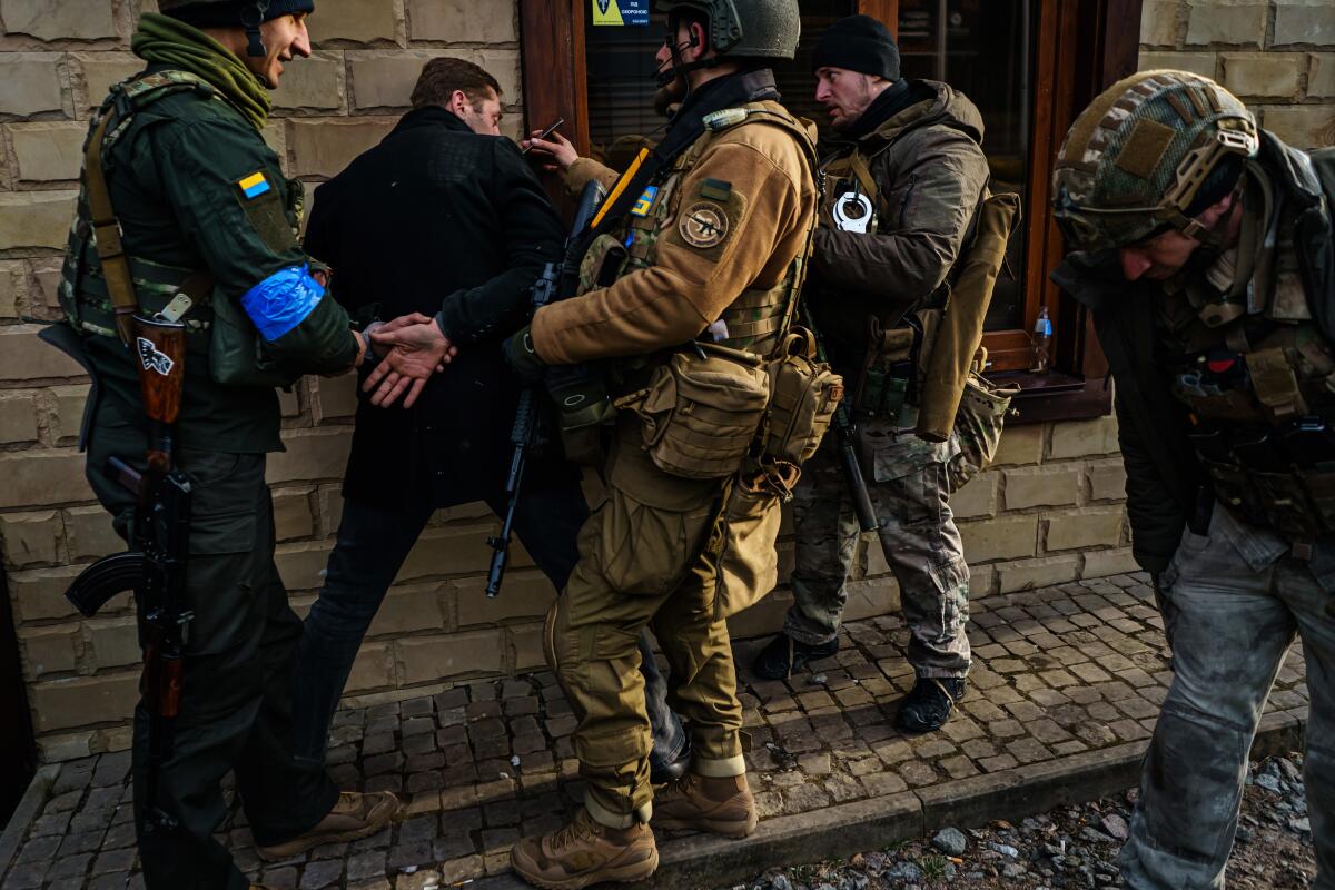 Ukrainian soldiers detain a man whom they say is a criminal, at a checkpoint Saturday in Irpin.