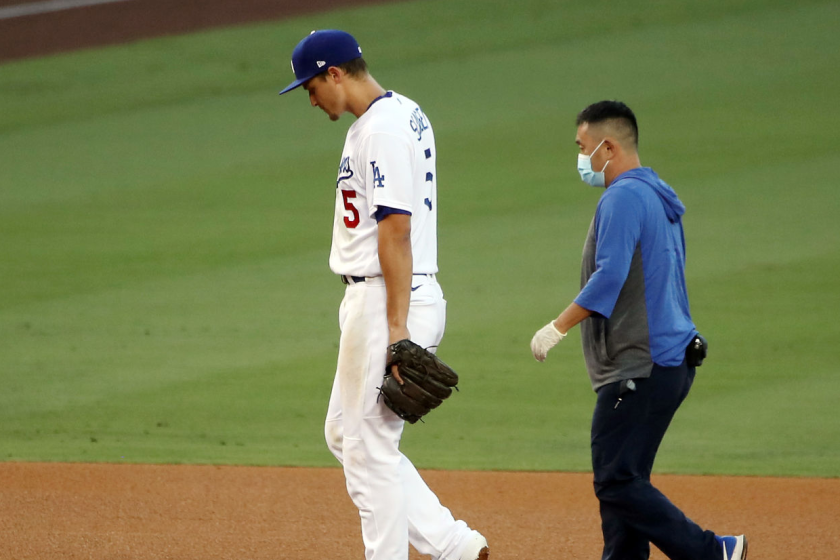 Dodgers shortstop Corey Seager walks off the field with a team trainer.