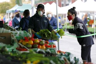 At the Farmers Market in Little Italy on Saturday, April 4, 2020, Stephen Clark from JR Organics helped Lori Vanderlinden select fresh produce while standing behind the tape. Grocery vendors are required to wear a face mask and customers could no longer hand select the produce for themselves.