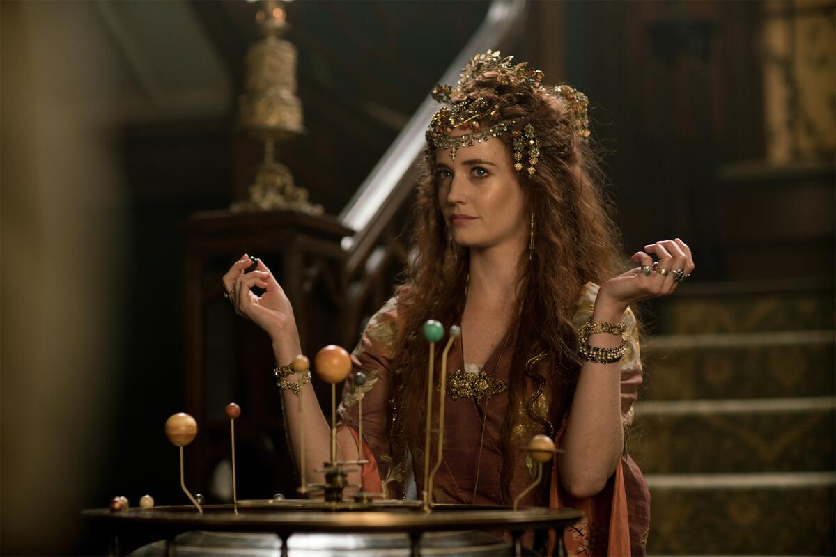 Actress Eva Green in an ornate headdress before a model of the solar system.