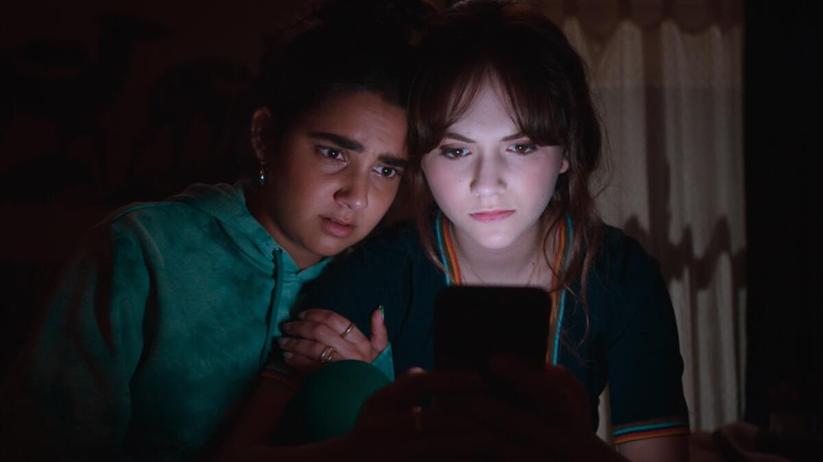 Geraldine Viswanathan and Emilia Jones look at a screen in the movie "Cat Person."