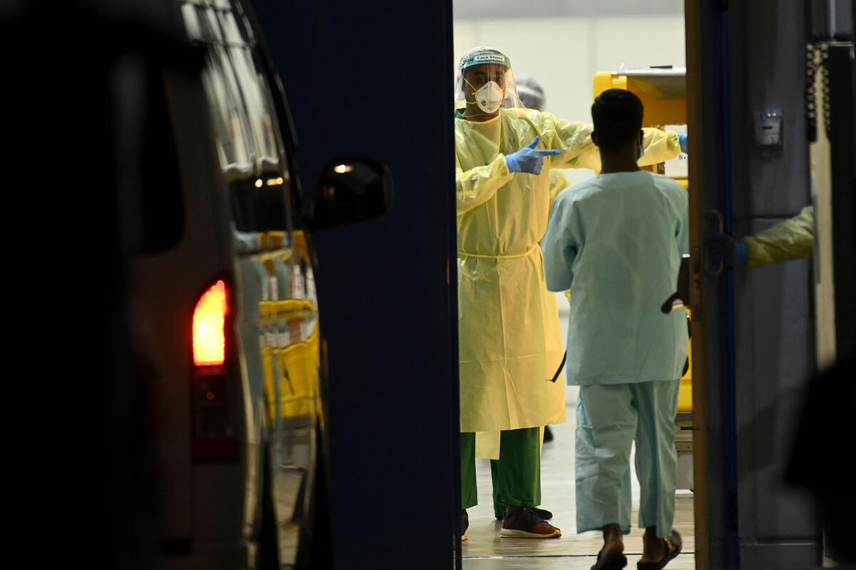 Medical staff wait for COVID-19 patients to be transferred to a temporary hospital in Singapore.