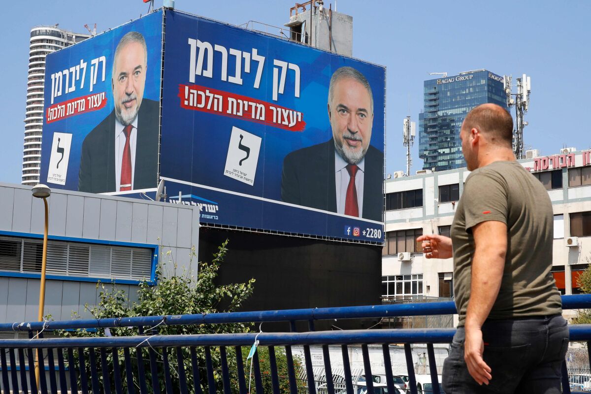 A man walks below an electoral billboard bearing the image of Yisrael Beiteinu party leader Avigdor Lieberman in Tel Aviv on Sept. 2, 2019. The writing in Hebrew reads: 'Only Lieberman will stop a theocracy.' Israel votes on Sept. 17 in its second election in five months, determining whether to extend Prime Minister Benjamin Netanyahu's term as the country's longest-serving prime minister.