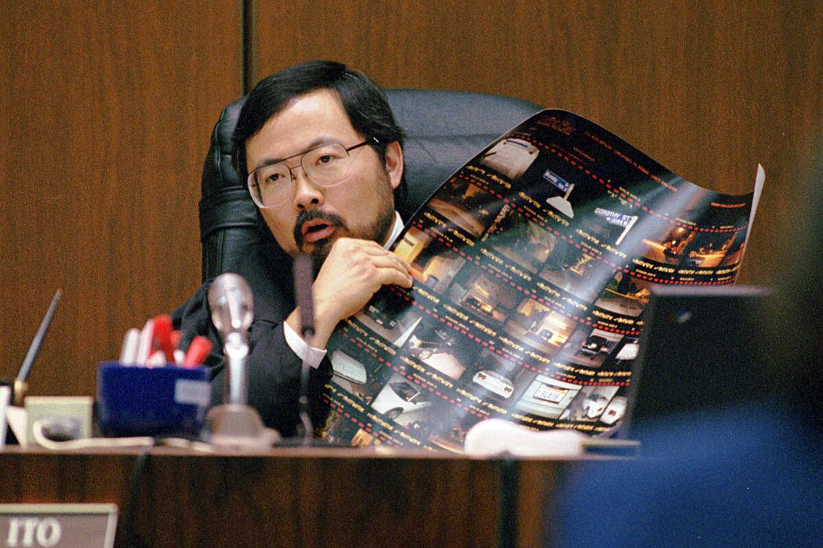 Judge Lance Ito holds up an enlarged proof sheet of crime scene photos during O.J. Simpson's double-murder trial in Los Angeles.