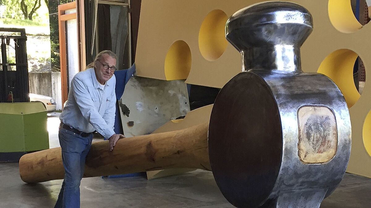 Artist Doug Unkrey is seen in 2017 with the giant hammer he created at his studio in Geyserville, Calif.