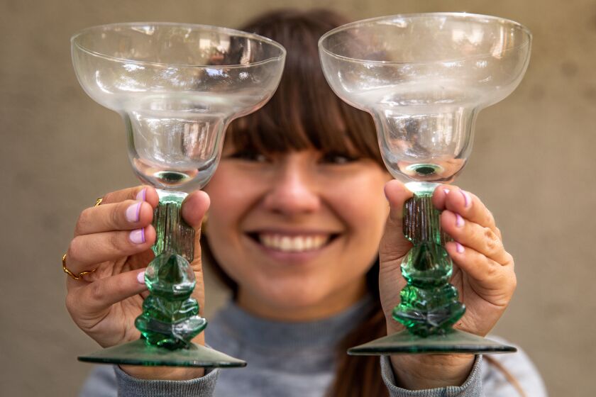 LOS ANGELES, CA-MARCH 31, 2023: Amy Solomon holds up a cocktail glasses she purchased while shopping at an estate sale on Alcyona Dr. in Los Angeles. Solomon runs a popular TikTok channel called Estatesalefreeks. (Mel Melcon / Los Angeles Times)