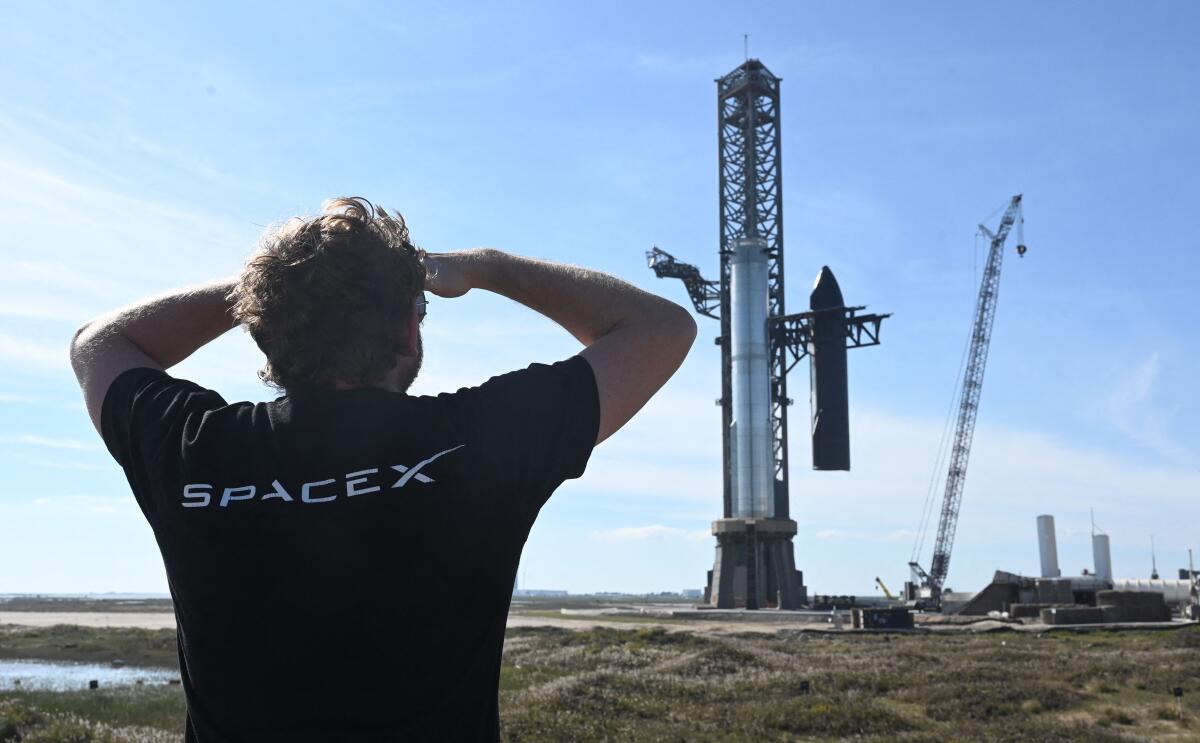 A person looks on at SpaceX's huge Super Heavy-Starship on a launch pad.
