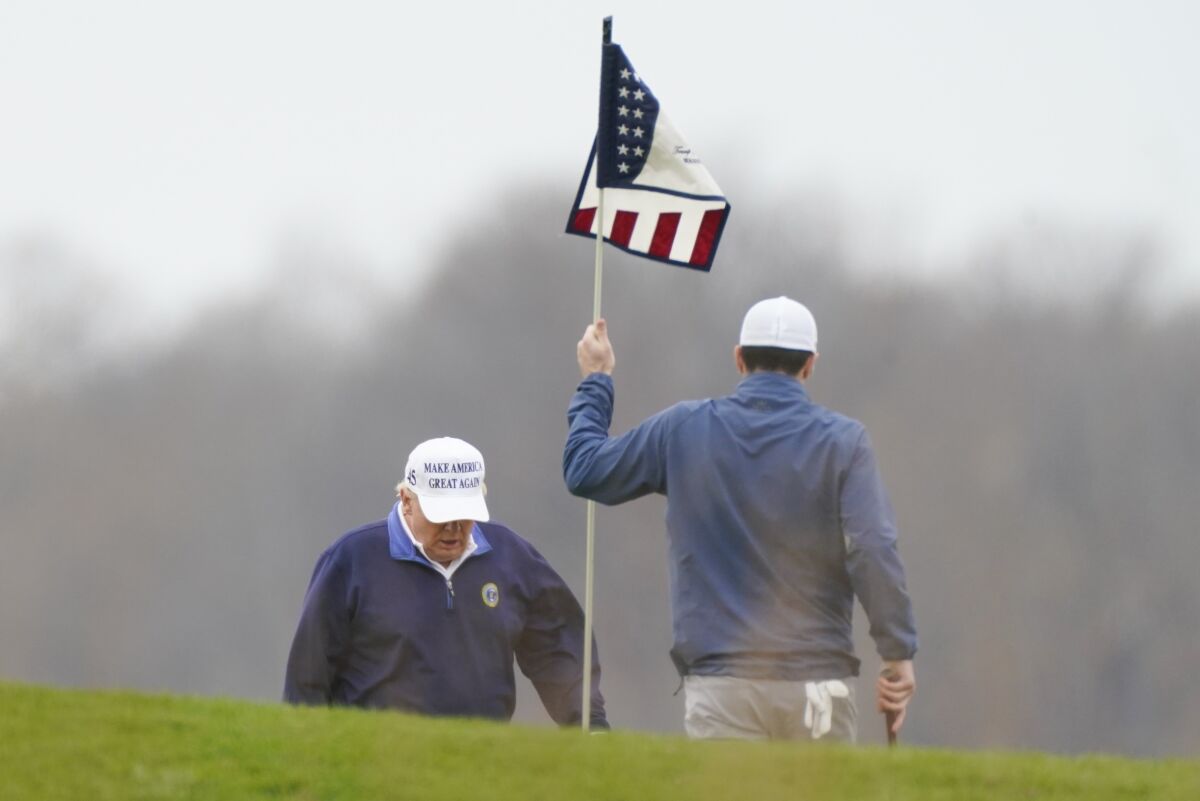 President  Trump walks on a golf course.