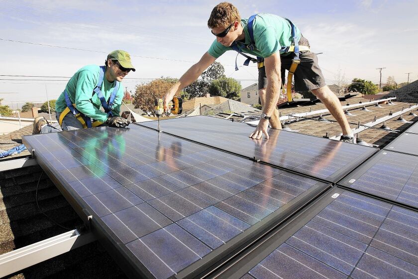 Solarcity workers Joey Ramirez, left, and Taran Stone install solar modules on the roof of a Long Beach home.