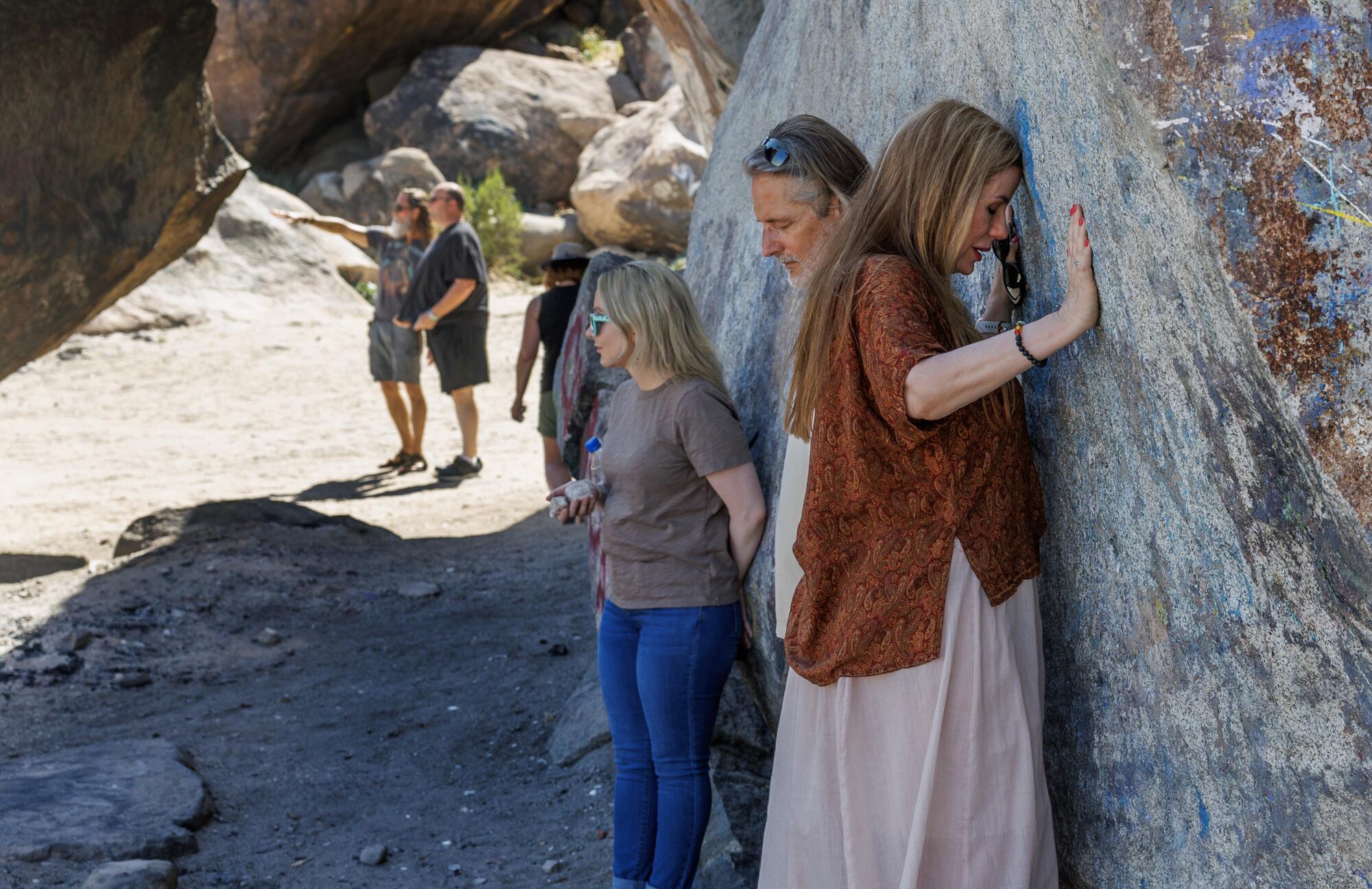 Men and women from a UFO convention lean on Giant Rock to "feel resonance." 