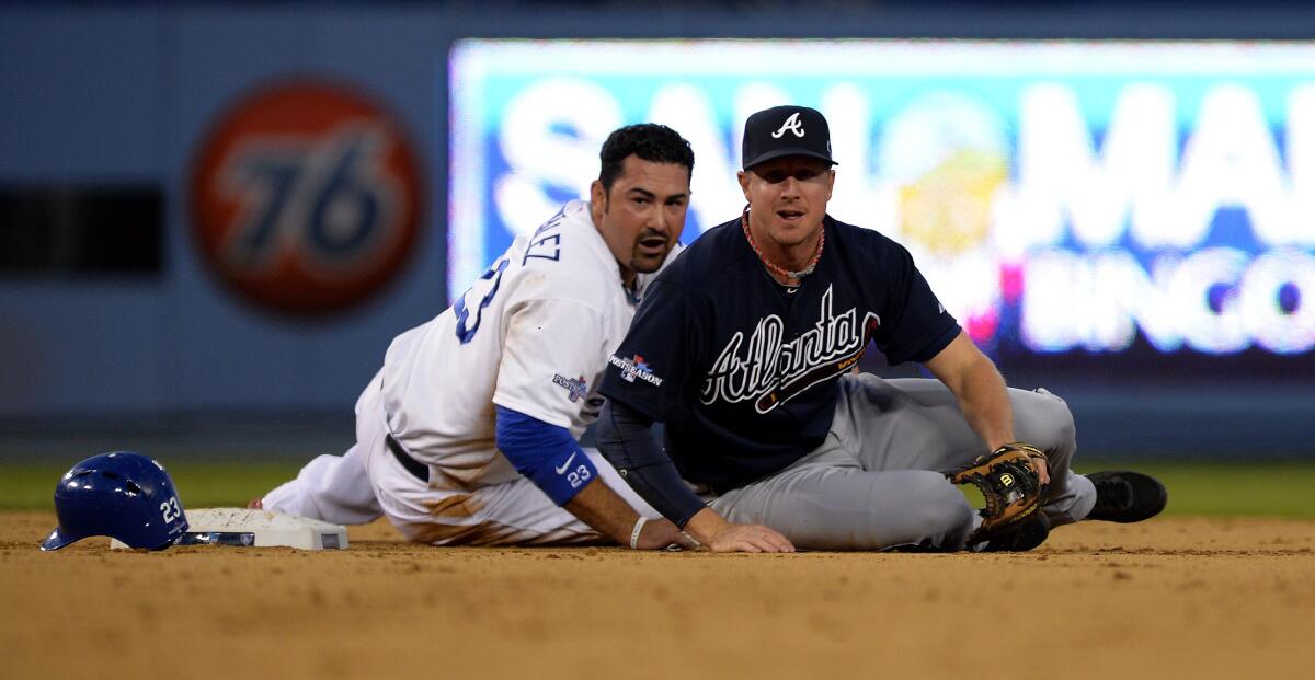 Dodgers' Adrian Gonzalez and Atlanta's Elliot Johnson watch from the ground after Gonzalez was tagged out.