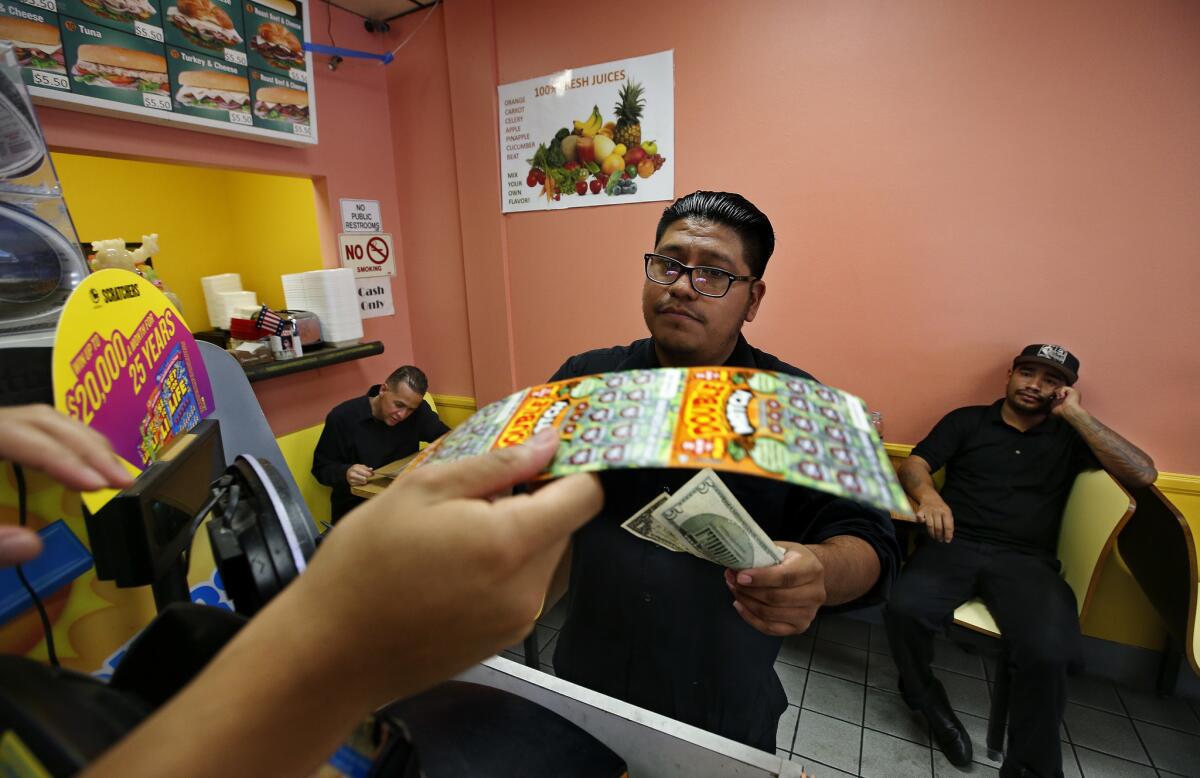 Mike Luna, a waiter at Frida, a Mexican restaurant in the Americana at Brand shopping center in Glendale, buys a scratchers lottery ticket at Christina Donuts.