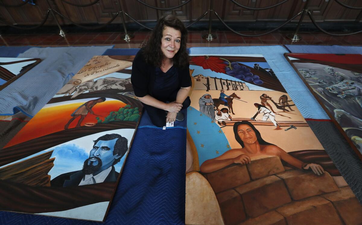 Barbara Carrasco kneels with two sections of her 43-panel mural, "L.A. History: A Mexican Perspective (1981)."