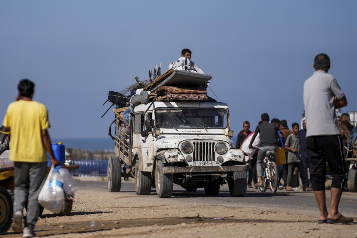 Palestinians carry belongings in bags and on a truck.