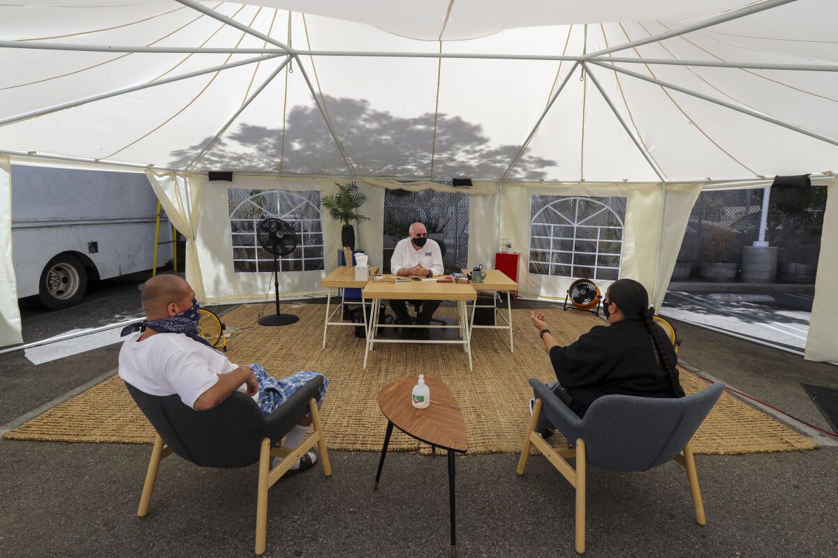 Father Greg Boyle, center, of Homeboy Industries is running the operation from a tent in the parking lot. 