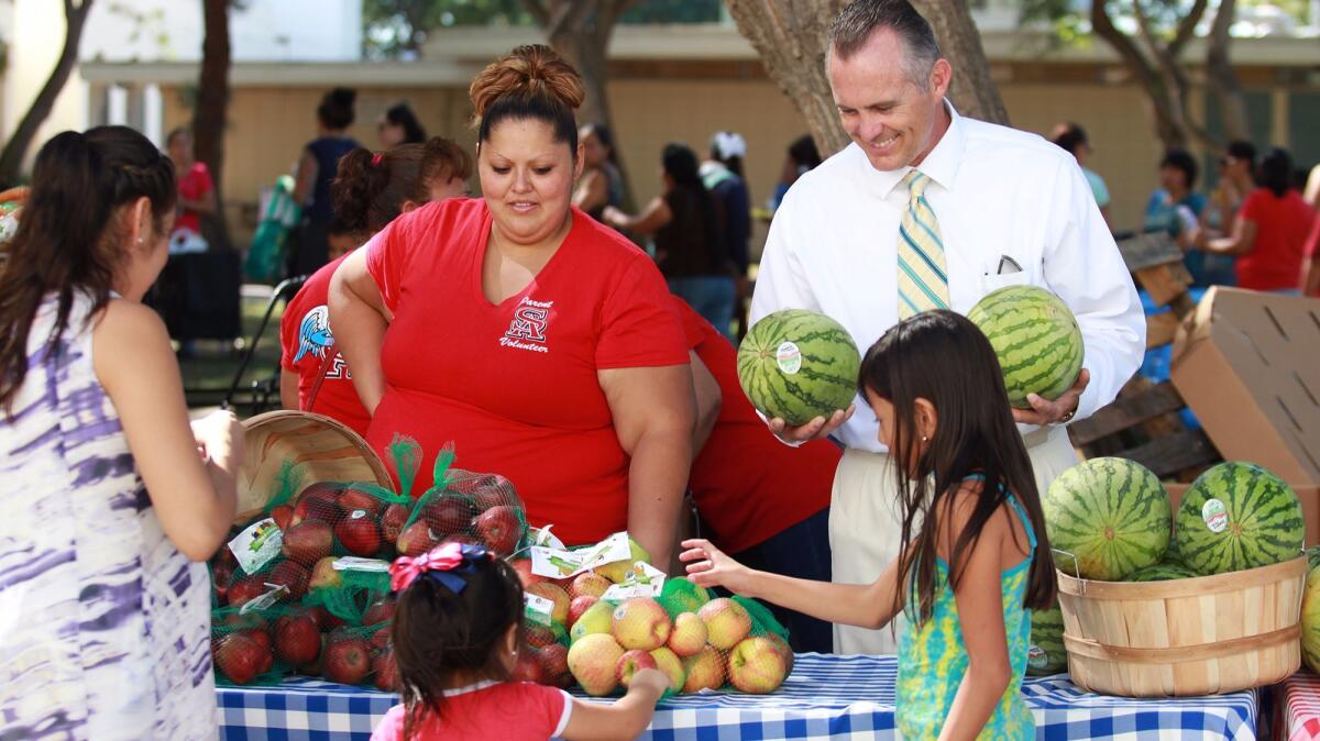 Assistant principal Gannon Burks, right, helps distribute food during a monthly farmers market at Santa Ana High School.