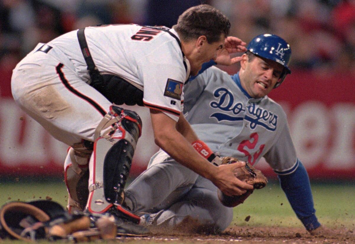Dodgers first baseman Eric Karros slides beneath the tag of San Francisco Giants catcher Kirt Manwaring to score during a game on July 25, 1994, at Candlestick Park.