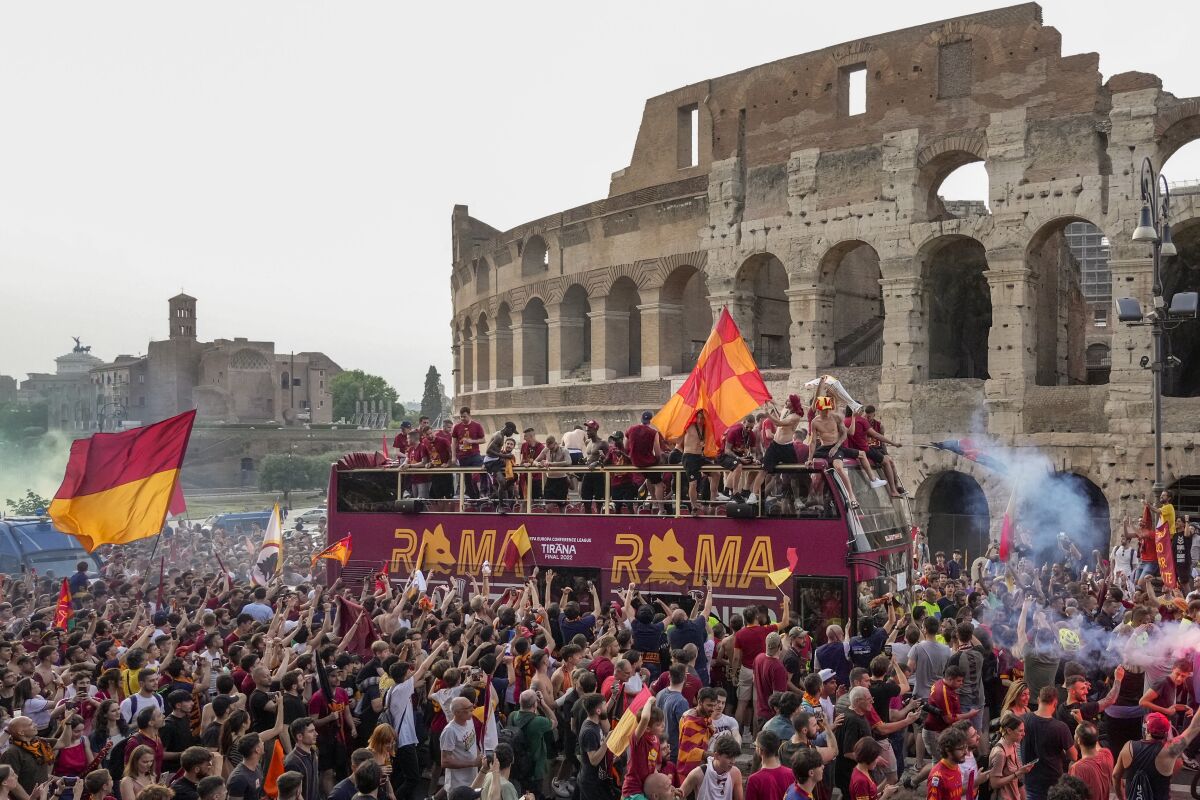 The bus with the AS Roma soccer team drives amid a crowd of jubilant supporters, in front of the Colosseum in Rome, Thursday, May 26, 2022, during the celebration for their victory in the Europe Conference League soccer final against Feyenoord in Tirana on Wednesday. (AP Photo/Gregorio Borgia)