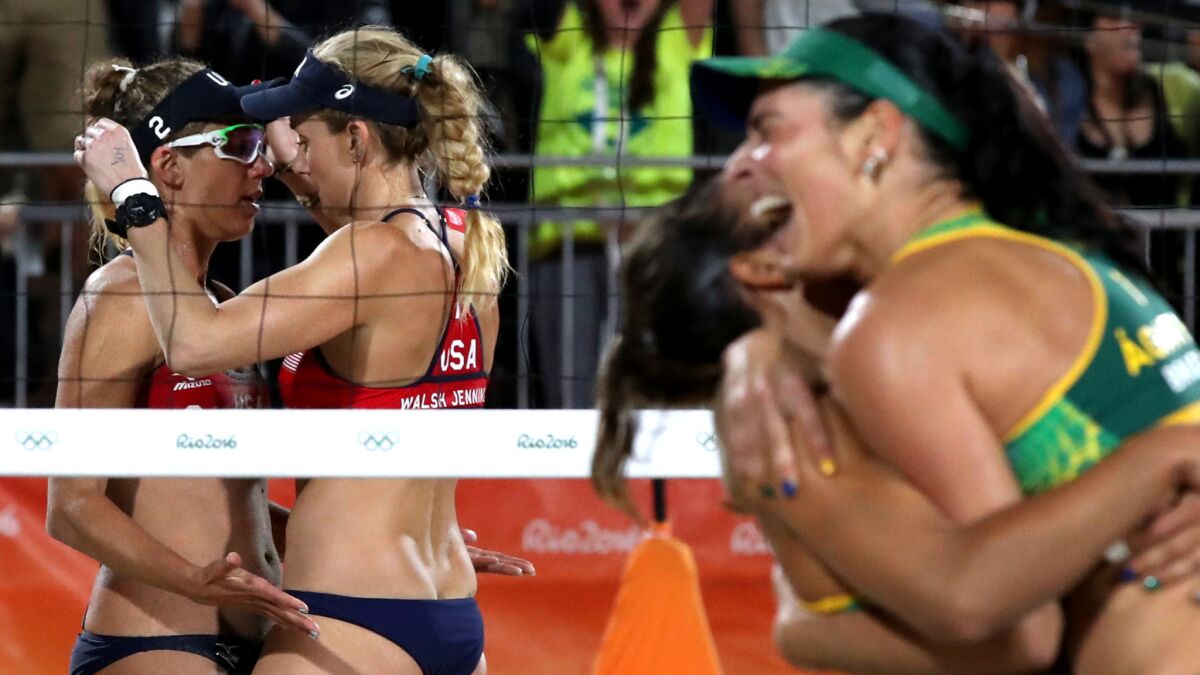 Americans Kerri Walsh Jennings, right, and April Ross console each other as Brazil's winning duo celebrate their victory in a women's beach volleyball semifinal.