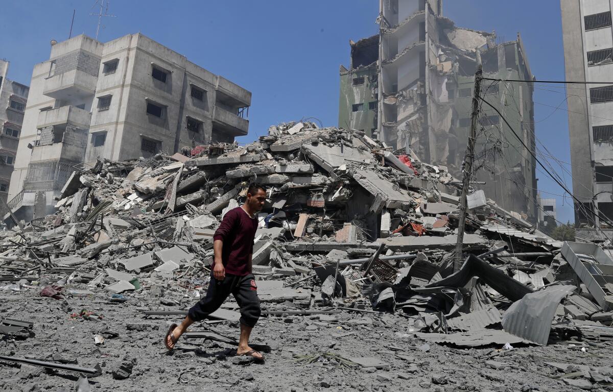A huge pile of rubble and damaged high-rises serve as the backdrop to a man walking by