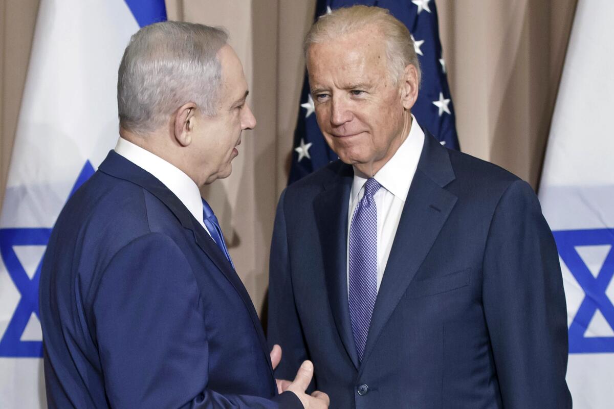 Benjamin Netanyahu speaks with Joe Biden in front of Israeli and American flags