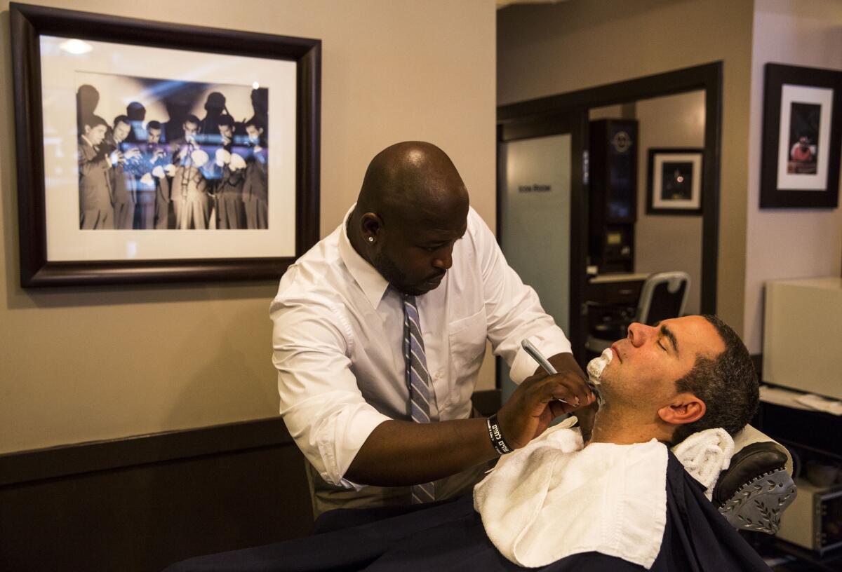Barber Ron Randle shaves Brad Small's face with a straight edge razor at The Shave in Beverly Hills.