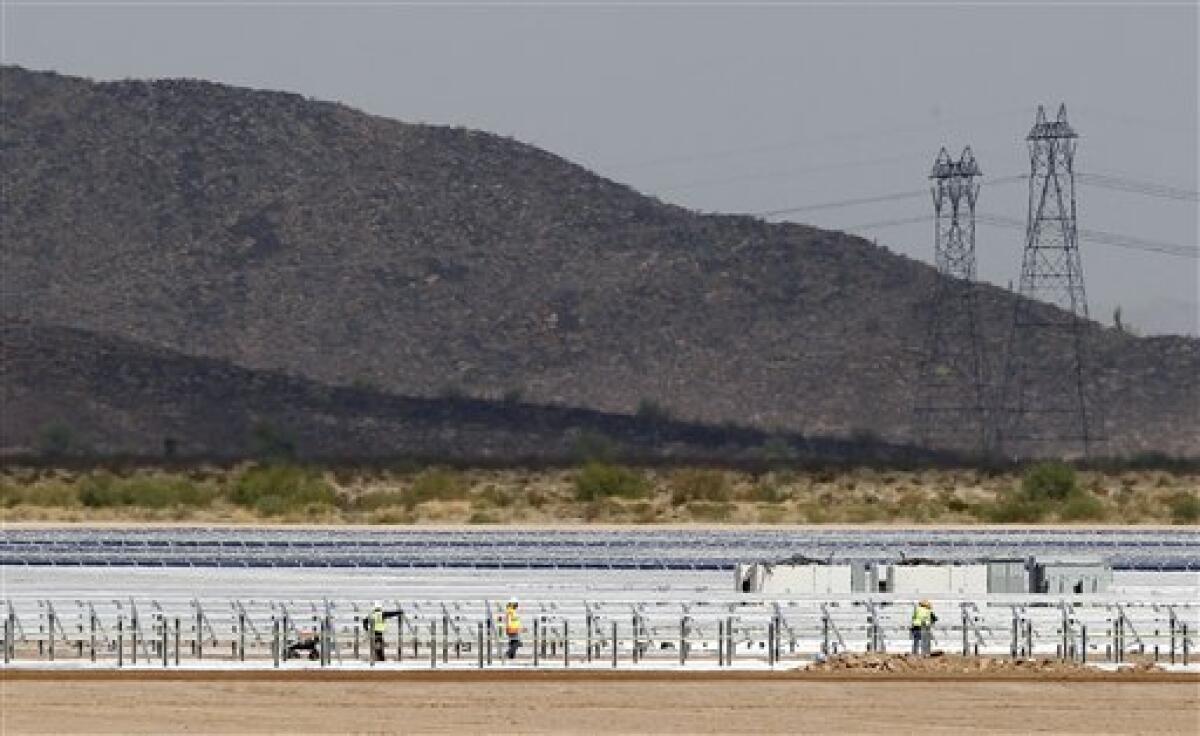 Workers install rows of solar panels at the Mesquite Solar 1 facility in Arlington, Ariz., in 2011.