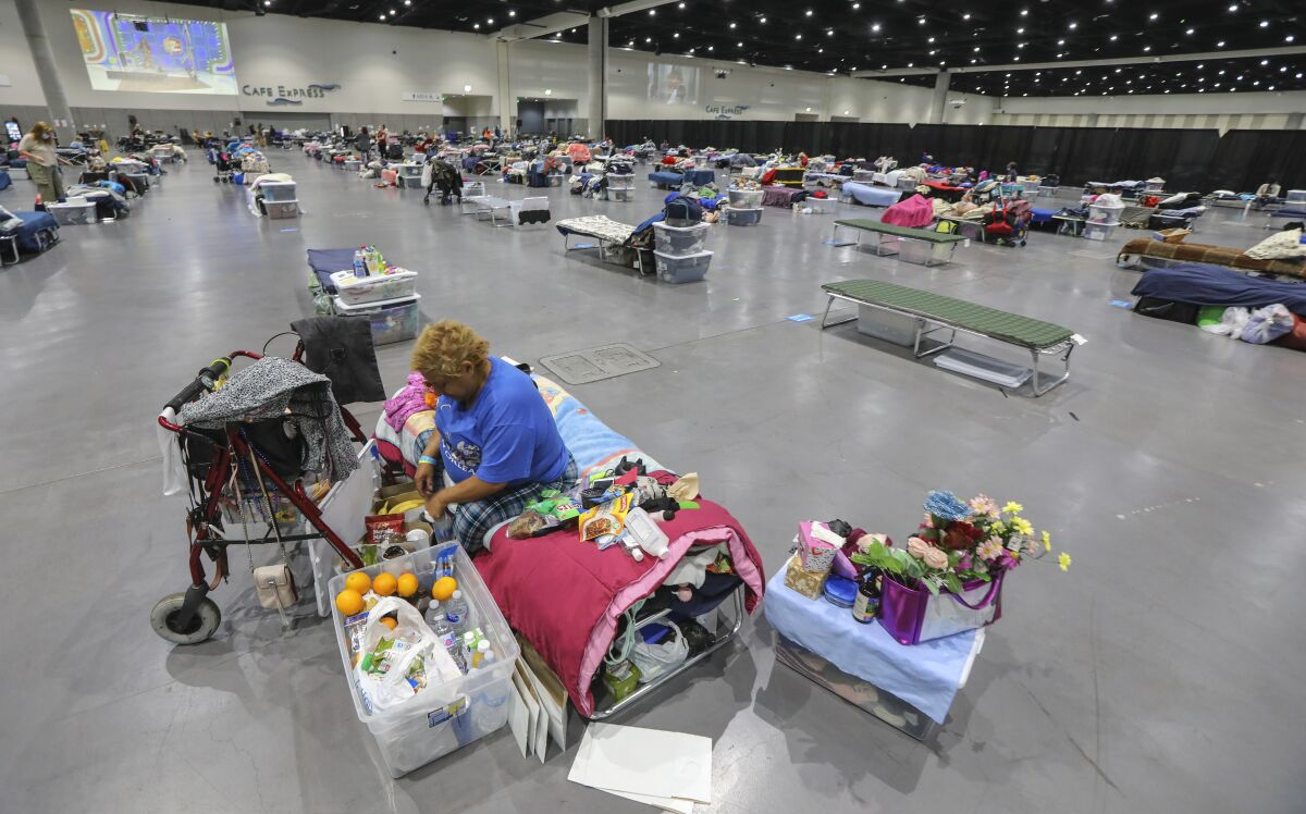 Letisha Vazquez goes through her belongings at the Convention Center, where people and cots are spaced apart