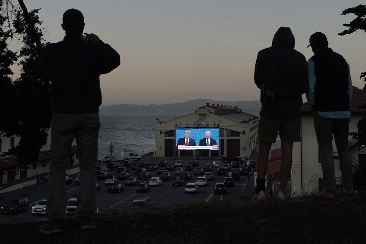 People watch a debate between President Trump and Joe Biden on an outdoor screen in San Francisco.