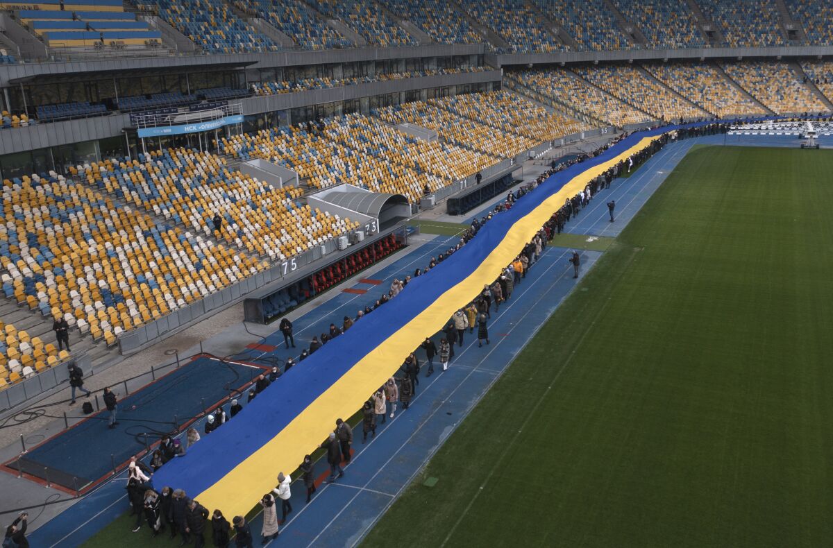 A 200 meter long Ukrainian flag is unfolded at the Olympiyskiy stadium in Kyiv, Ukraine, Wednesday, Feb. 16, 2022. As Western officials warned a Russian invasion could happen as early as today, the Ukrainian President Zelenskyy called for a Day of Unity, with Ukrainians encouraged to raise Ukrainian flags across the country. (AP Photo/Efrem Lukatsky)