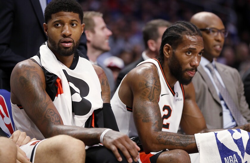 All-Star forwards Paul George, left, and Kawhi Leonard watch a game from the bench on Dec. 3, 2019.