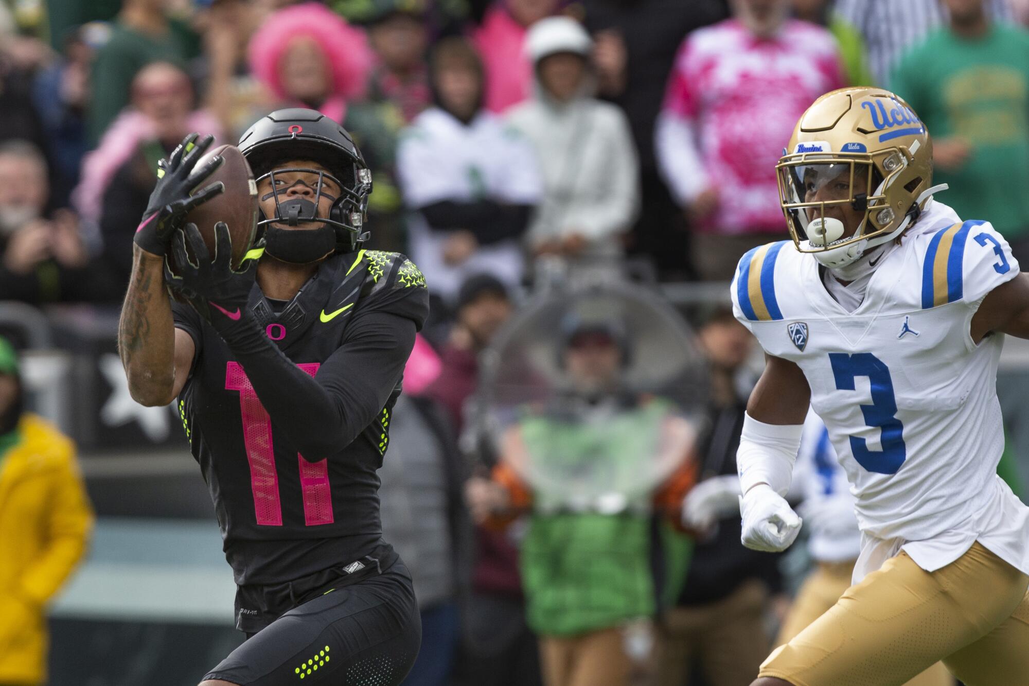 Oregon wide receiver Troy Franklin, left, hauls in a touchdown pass ahead of UCLA defensive back Devin Kirkwood.