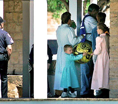 A guard watches over members of the Fundamentalist Church of Jesus Christ of Latter Day Saints as they walk along a covered porch at their temporary housing after an aggressive raid on their compound this month.