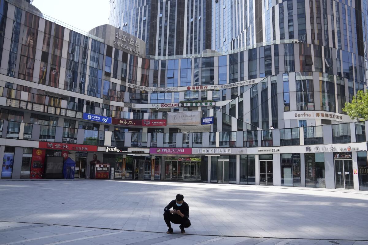 Un hombre con una mascarilla frente a un centro comercial vacío el lunes 2 de mayo de 2022 en Beijing. (AP Foto/Ng Han Guan)