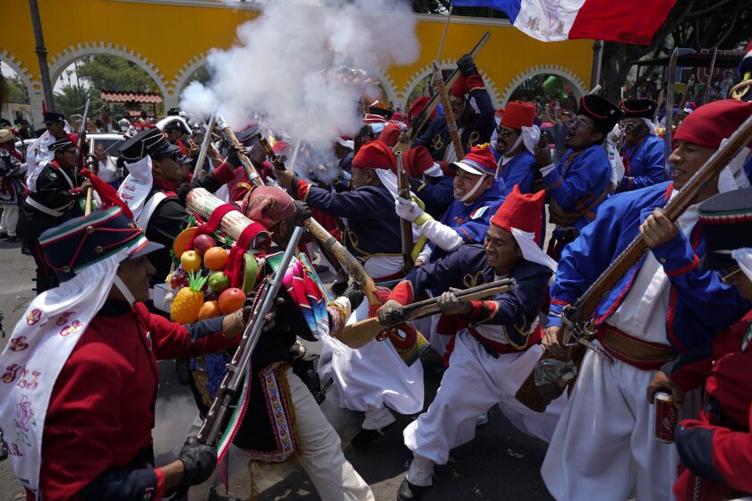 People dressed as Zacapoaxtla Indigenous soldiers clash with others playing the part of French soldiers as they reenact The Battle of Puebla as part of Cinco de Mayo celebrations in the Peñon de los Baños neighborhood of Mexico City, Thursday, May 5, 2022. Cinco de Mayo commemorates the victory of an ill-equipped Mexican army over French troops in Puebla on May 5, 1862. (AP Photo/Eduardo Verdugo)