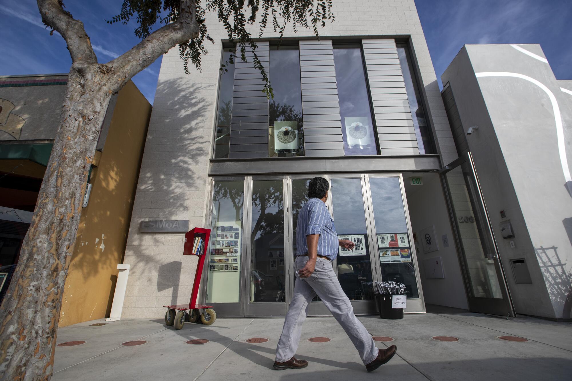 A man walks in front of a silver building