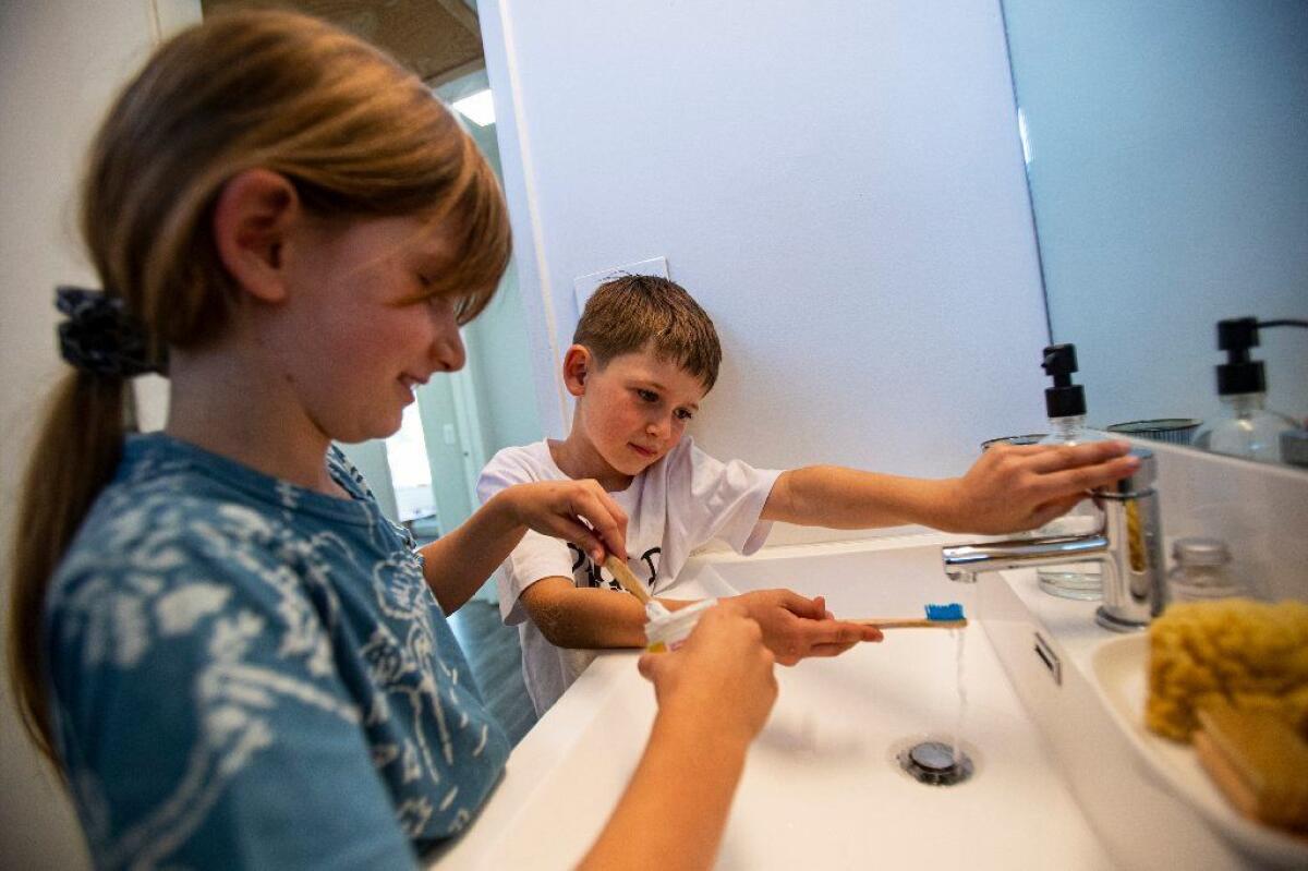 At home, Isla and James apply toothpaste made from tablets stored in a glass jar onto their bamboo toothbrushes.