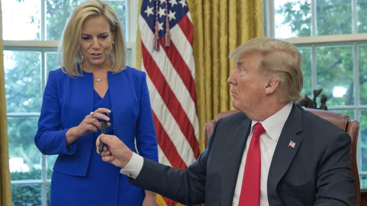 In a June photo, President Trump hands Homeland Security Secretary Kirstjen Nielsen the pen he used to sign the executive order to end family separations.