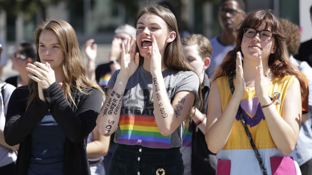 Azusa Pacific University students Alissa Gmyrek, Cayla Hailwood and Rachel Davis cheer on speakers during an LGBTQ support rally at the college on Monday.