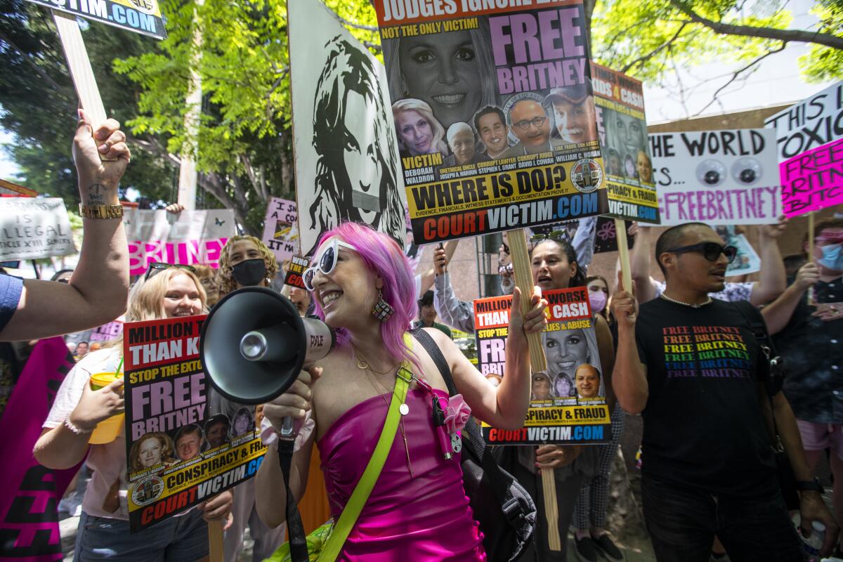 A person with a megaphone stands in the center of a crowd with Free Britney signs