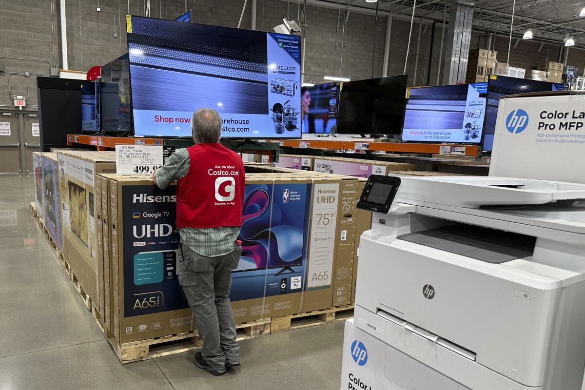 An employee checks a big-screen TV display in a Costco warehouse store