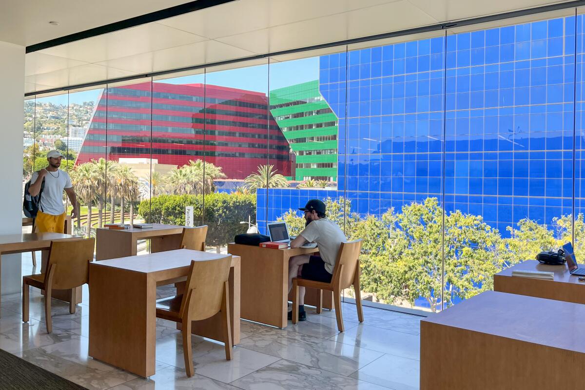 Desks and chairs next to a window that looks out at the Pacific Design Center's red, green and blue buildings.