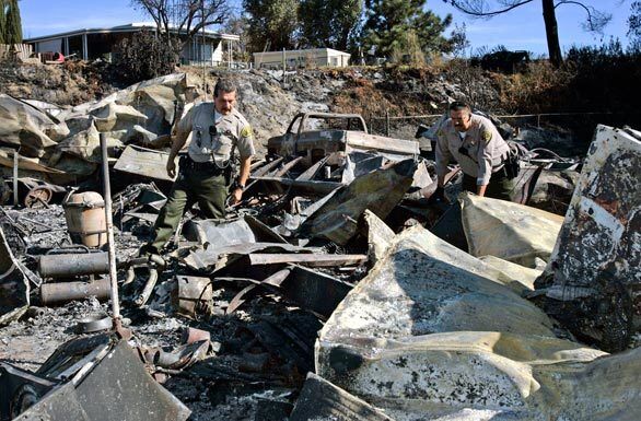 Los Angeles County sheriff's deputies Armando Guzman, left, and Jose Belmares search for any evidence of an unaccounted person after the fire that swept through Sky Terrace Mobile Lodge.