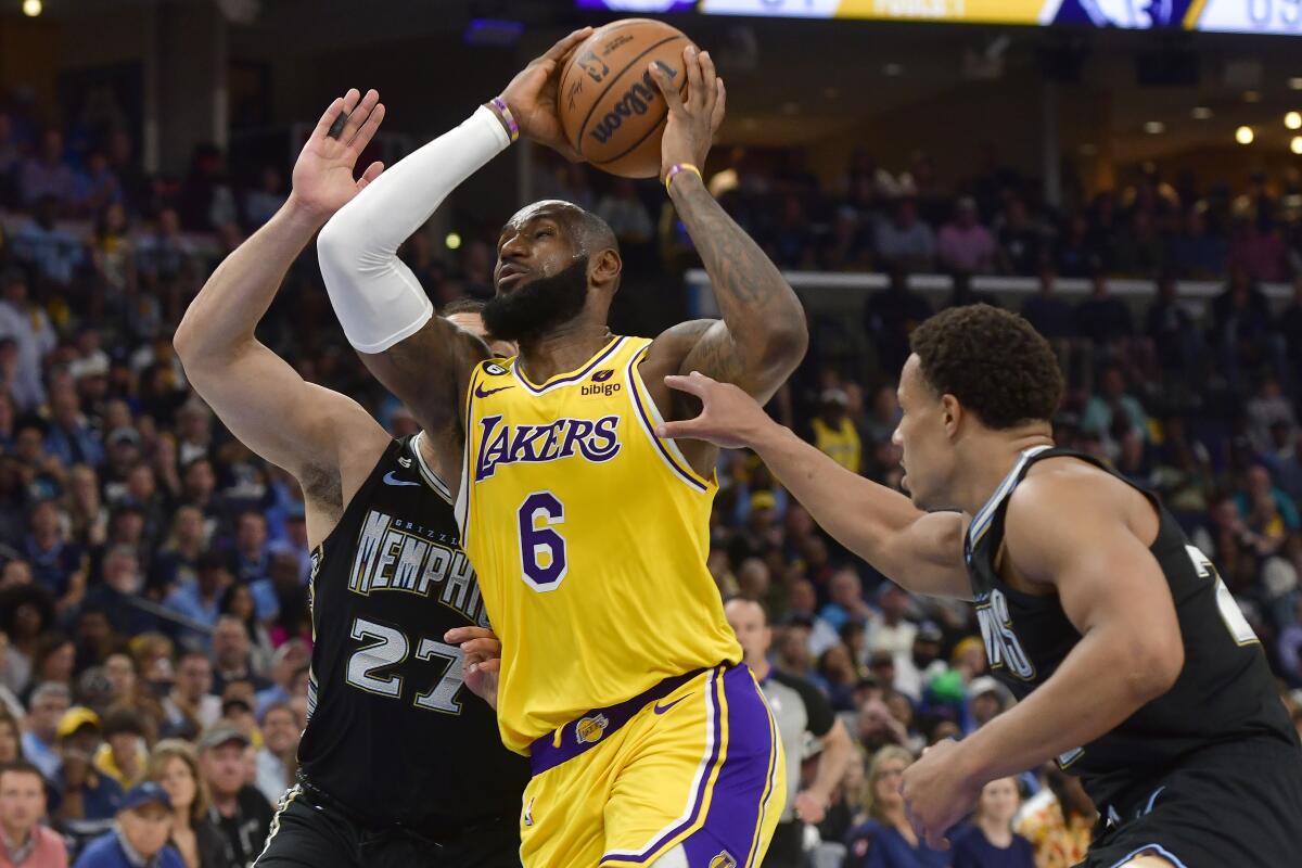 Lakers forward LeBron James, center. drives between Grizzlies forward David Roddy, left, and guard Desmond Bane.